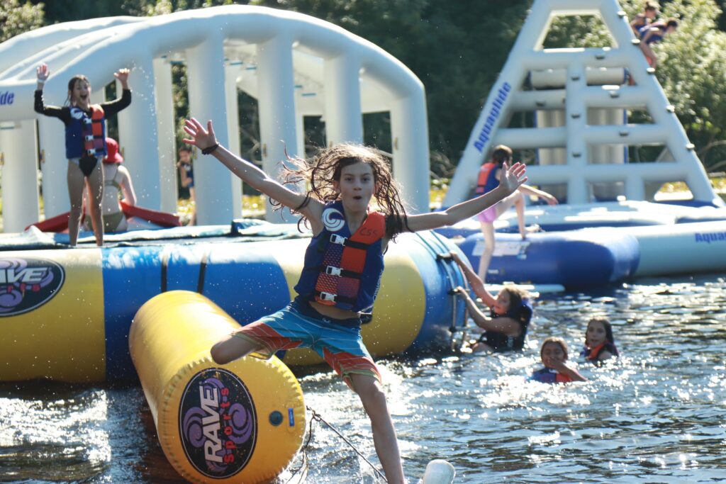 child jumping into water off inflatable