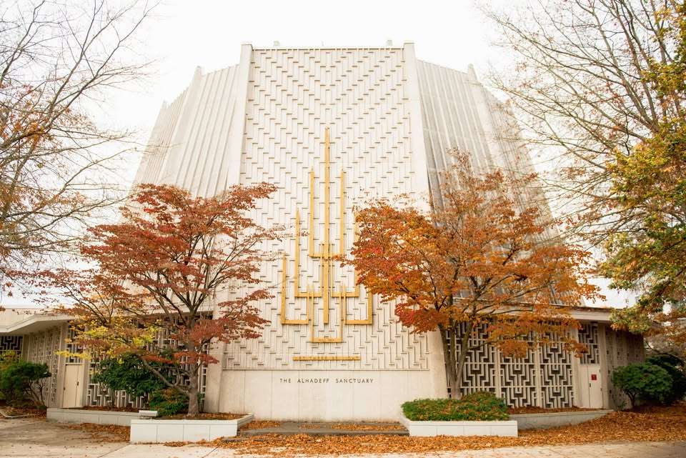 Front view of The Alhadeff Sanctuary with a geometric white facade and autumn trees in fall foliage.