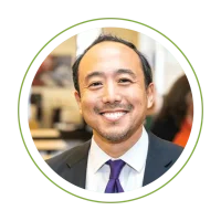 Smiling man in a suit with a purple tie, circular crop on a green background