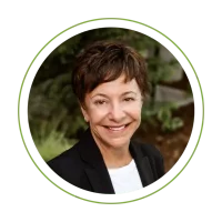 Smiling woman in a black blazer and white shirt, portrait photo inside a green circular frame.